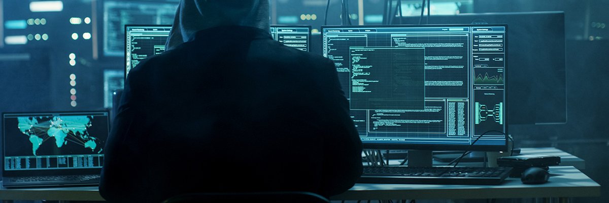 Dangerous Hooded Hacker Breaks into Government Data Servers and Infects Their System with a Virus. His Hideout Place has Dark Atmosphere, Multiple Displays, Cables Everywhere.